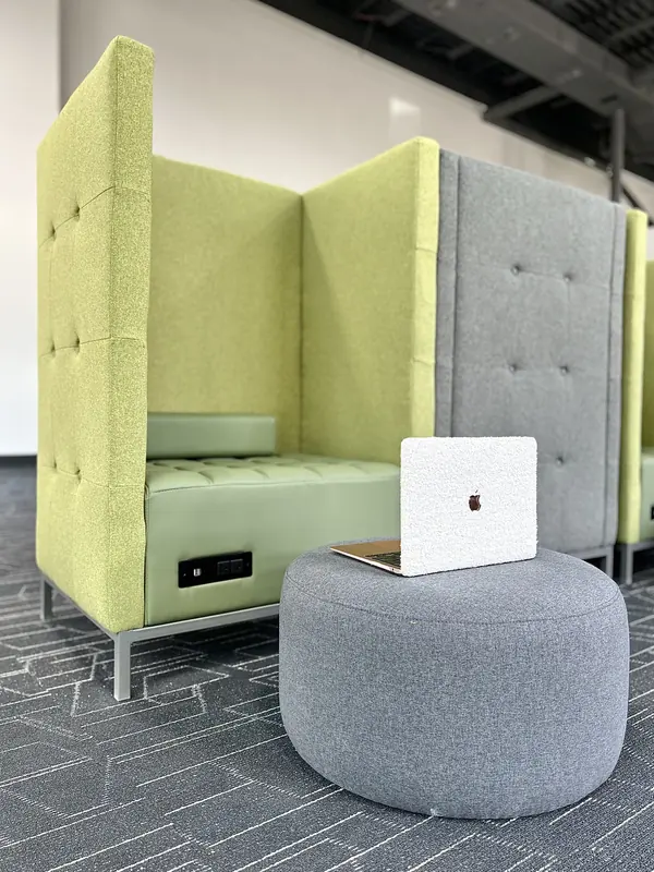 Inside a coworking booth: an open laptop on the bench with a power outlet in the panel