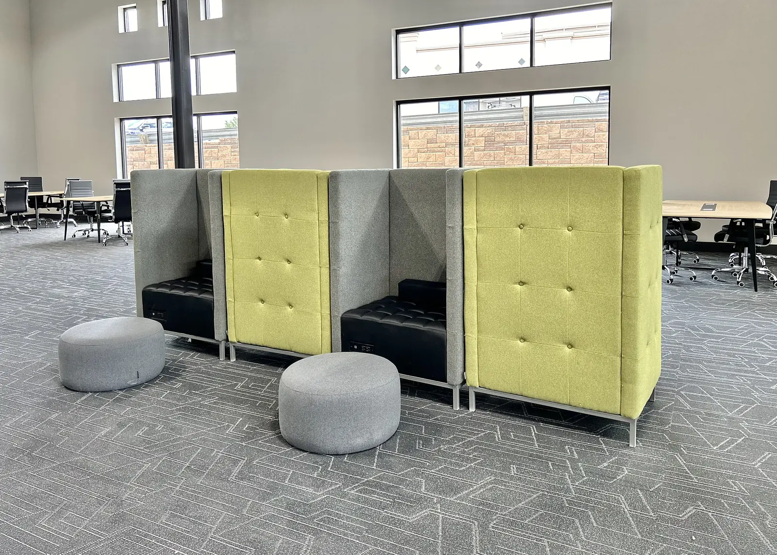A row of high-backed work booths, with the meeting room tables beyond them