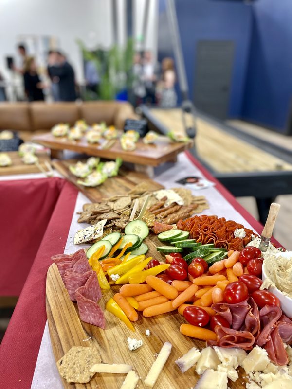 A catering board of cured meats, cheese and vegetables laid out on a long table