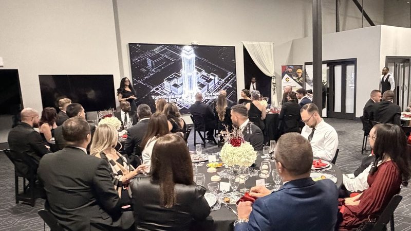 Guests at a black-tie dinner facing our LED wall, a city skyline filling it, with two flatscreen TVs beside it