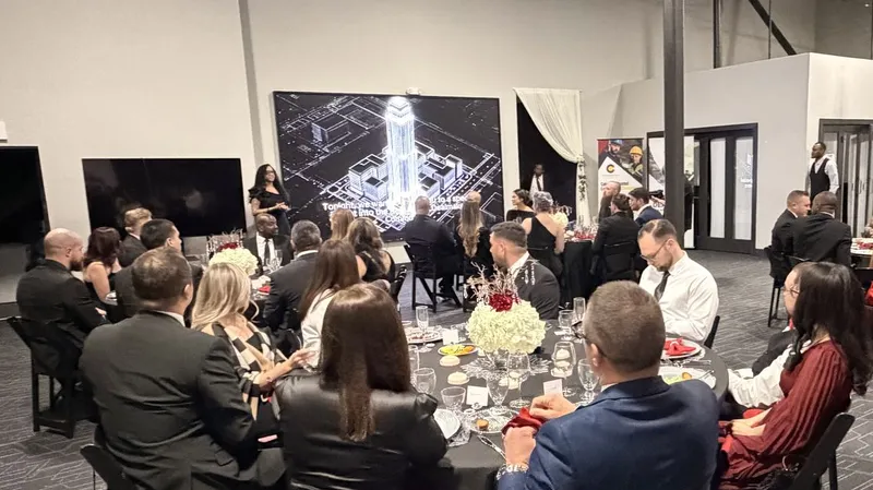 Guests at a black-tie dinner facing our LED wall, a city skyline filling it, with two flatscreen TVs beside it