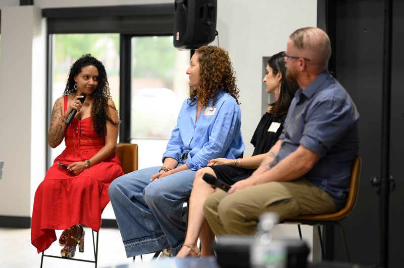 Four panelists seated in a row, one speaking into a microphone