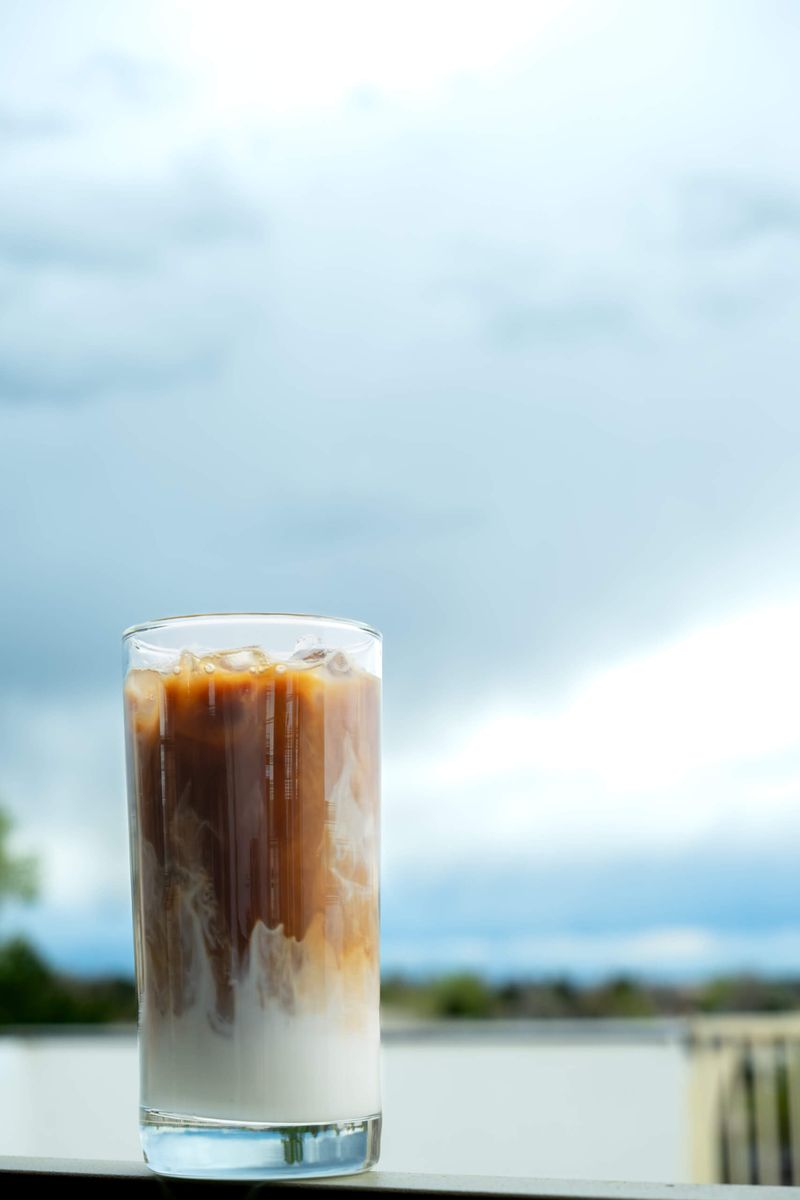 An iced latte on a ledge against a cloudy sky