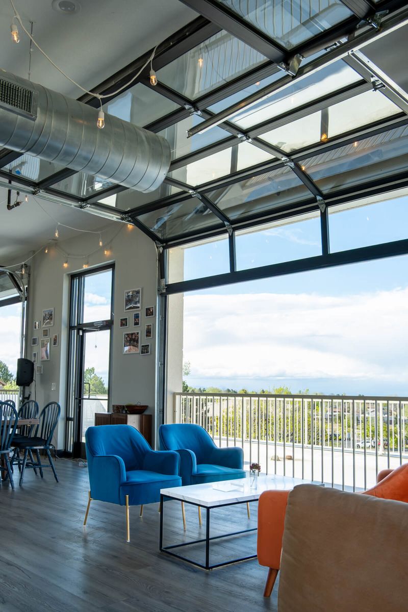 Blue armchairs beside an open garage door, with string lights and a silver duct overhead