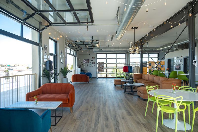The second floor at Happy Crew Coffee House: orange sofas, lime green chairs, string lights, and a wall of garage-door windows