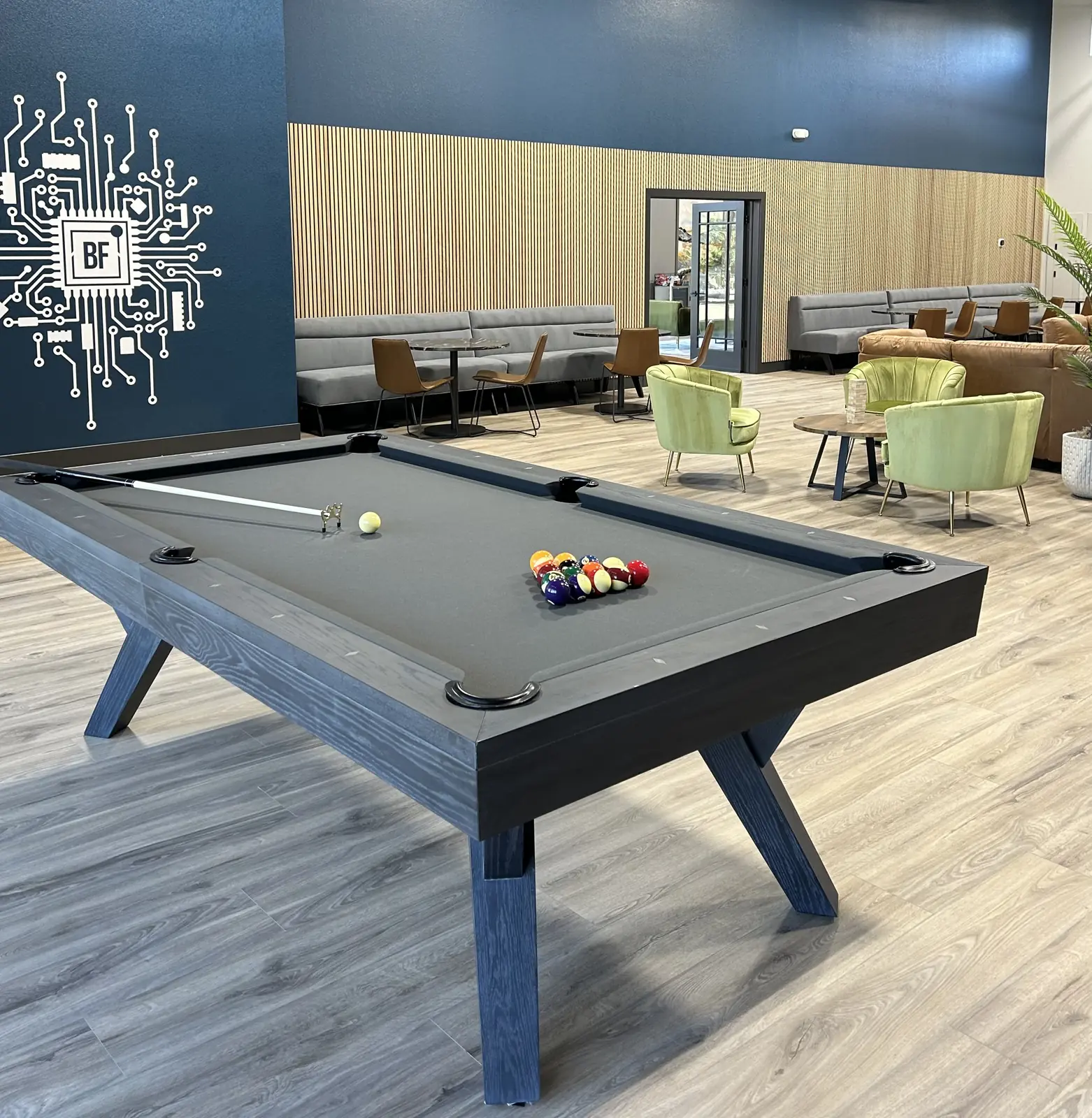The pool table on the lounge floor, racked and waiting under the circuit-board wall