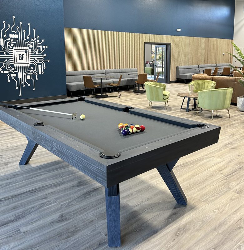 The pool table on the lounge floor, racked and waiting under the circuit-board wall