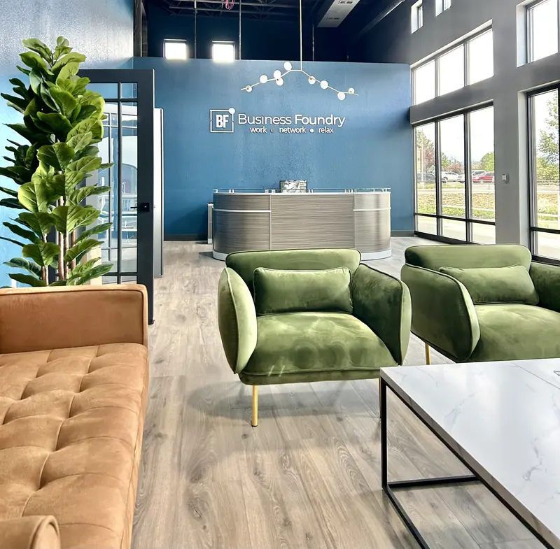 Business Foundry reception, with the wall sign and two green armchairs