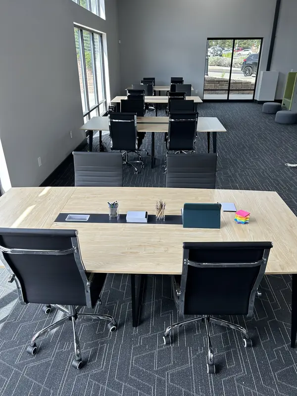 The meeting room set up as a training room, with separate tables in rows and pens and notepads on the front one